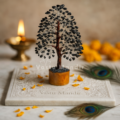 Black Tourmaline Vastu Tree (10-11  Inch) for protection, grounding, and negative energy absorption. on a marble slab with 'Vastu Mandir' branding, surrounded by peacock feathers and a lit candle.