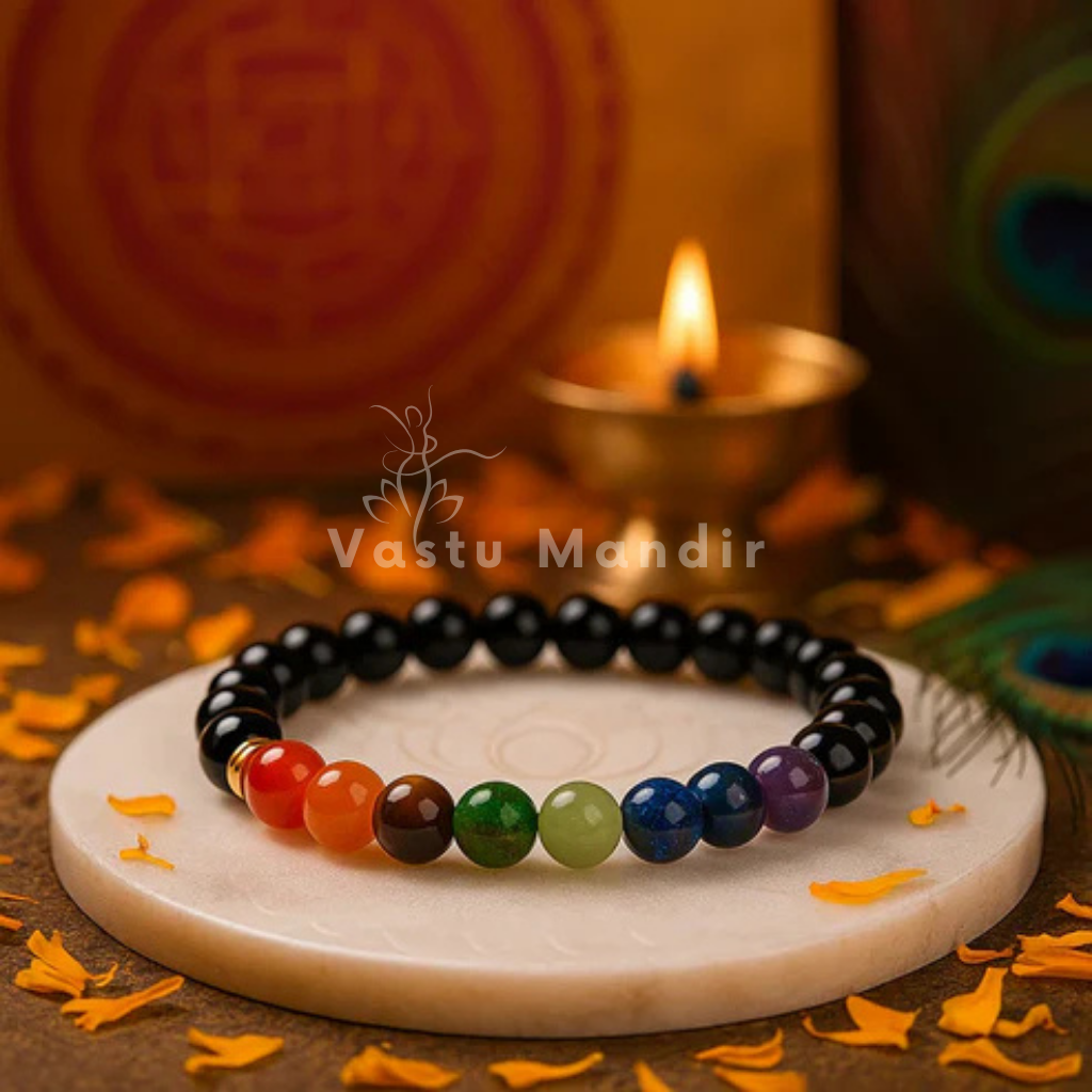 Chakra beaded bracelet on a marble slab with decorative elements and 'Vastu Mandir' branding.
