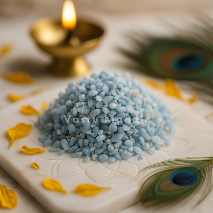 Angelite crystal chips on a white plate with yellow petals and a peacock feather, featuring the brand 'Vastu Mandir'.