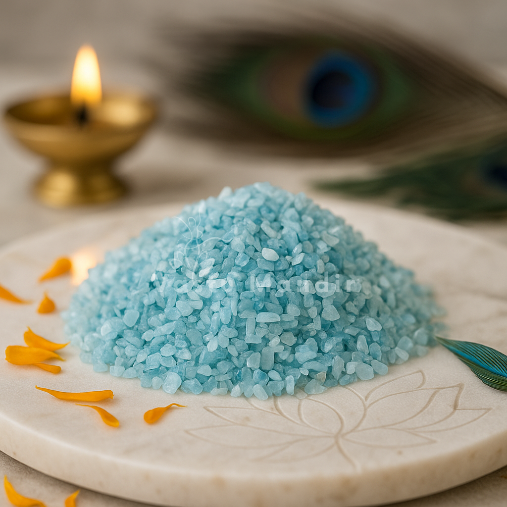 Aquamarine crystal chips arranged on a carved white plate with marigold petals and a softly lit diya