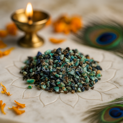 Small pile of Azurite stones on a decorative plate with a lit candle and peacock feather in the background.