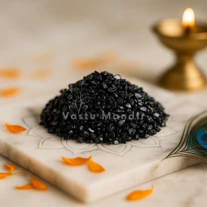 Black Tourmaline Vastu Chips on a decorative plate with a candle in the background