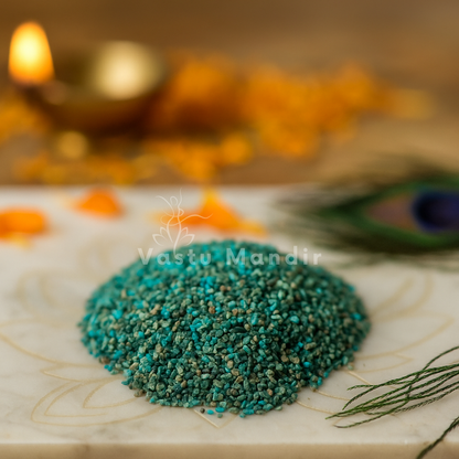 Blue Apatite Crystal Chips on a marble surface with a blurred background featuring lights and peacock feathers.