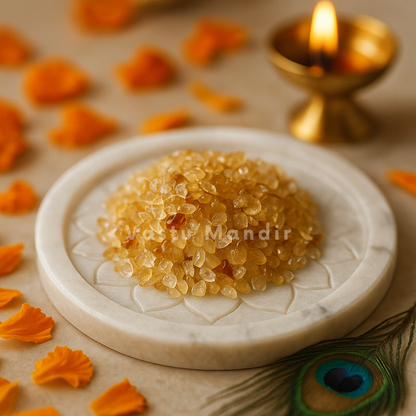 Citrine Crystal Chips on a marble plate, surrounded by orange petals and a lit gold lamp.