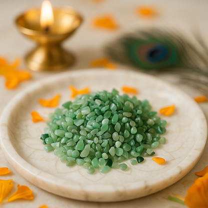 Green stones chips on a white plate with a lit candle and peacock feather in the background
