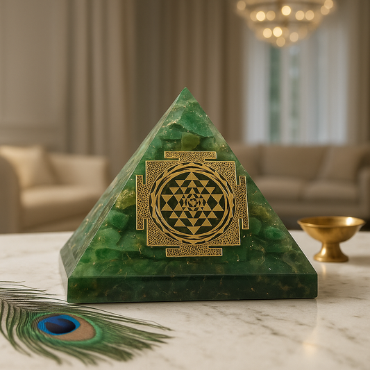 green mica shree yantra orgonite pyramid vastu remedy manifestation on a marble surface, peacock feather and gold bowl in background.