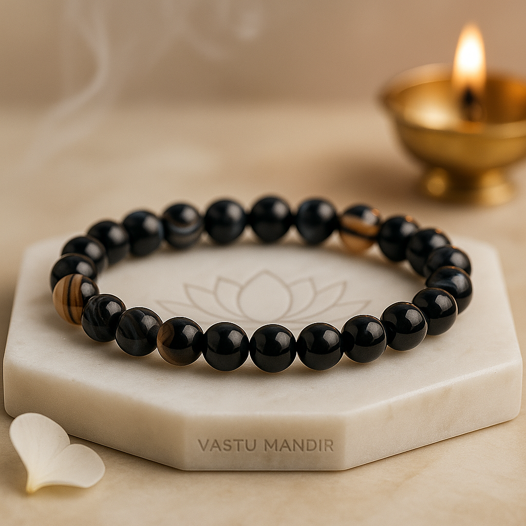 Black Agate 8mm bead bracelet on a marble stand with 'Vastu Mandir' branding, next to a lit candle.