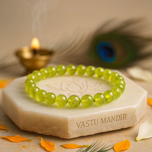 Natural peridot 8 mm crystal bead bracelet on a stone surface with 'Vastu Mandir' branding, surrounded by decorative elements.