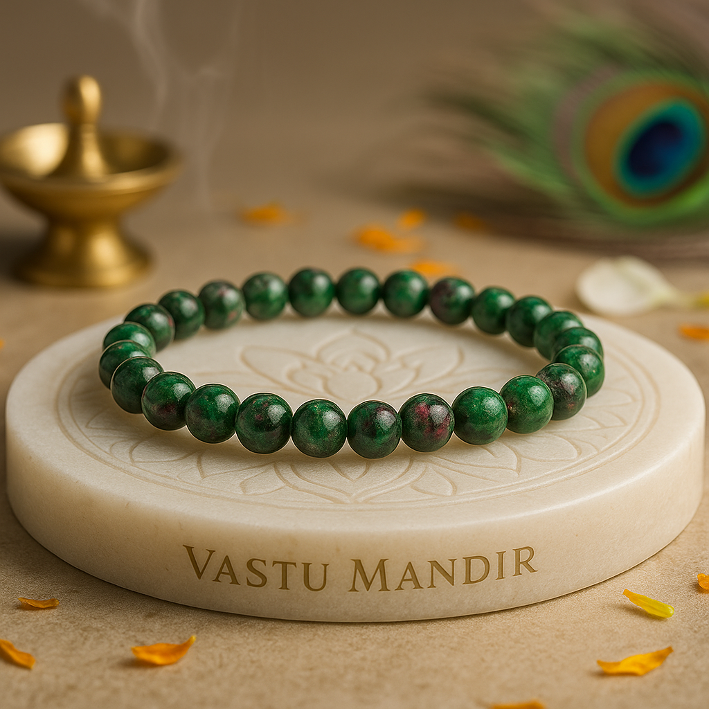 Green ruby zoisite 8mm bead bracelet on a 'Vastu Mandir' stone with a peacock feather and dia in the background.