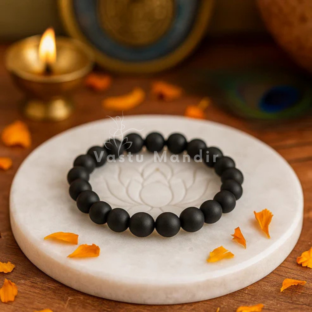 Shaligram Bracelet — 8mm Beads on a white marble coaster with Diwali decorations in the background.
