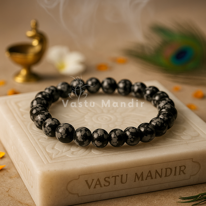 100% Natural Snowflake Obsidian beads with distinctive black base and white snowflake-like cristobalite inclusions on a 'Vastu Mandir' stone with decorative elements in the background