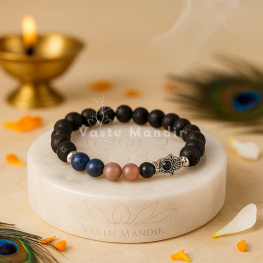 Natural Lava stone with mixed throat-energy crystals (blue/neutral tones) + metal spacers on a marble stand with 'Vastu Mandir' branding, surrounded by decorative elements.