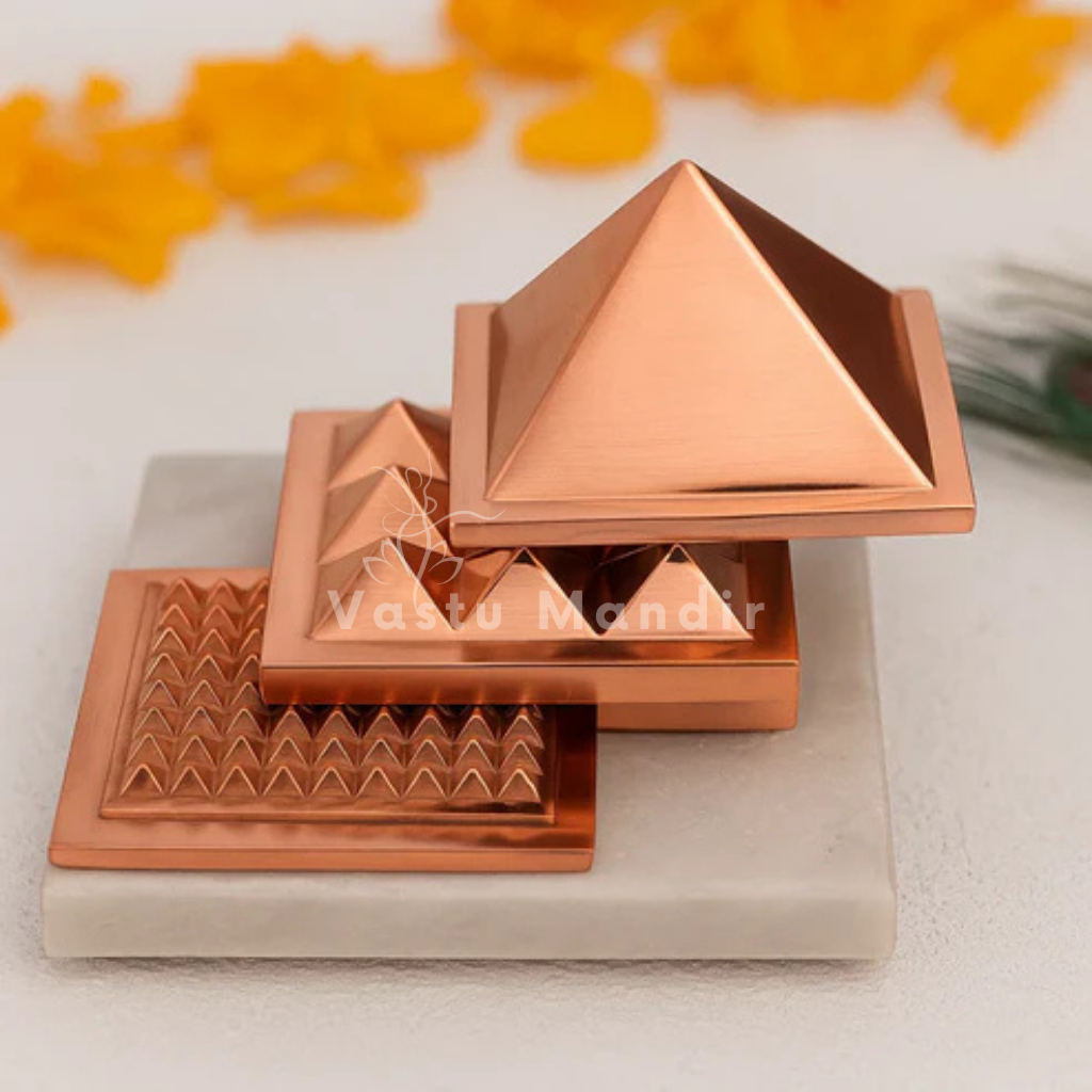 Copper pyramid on a white surface with blurred orange objects in the background