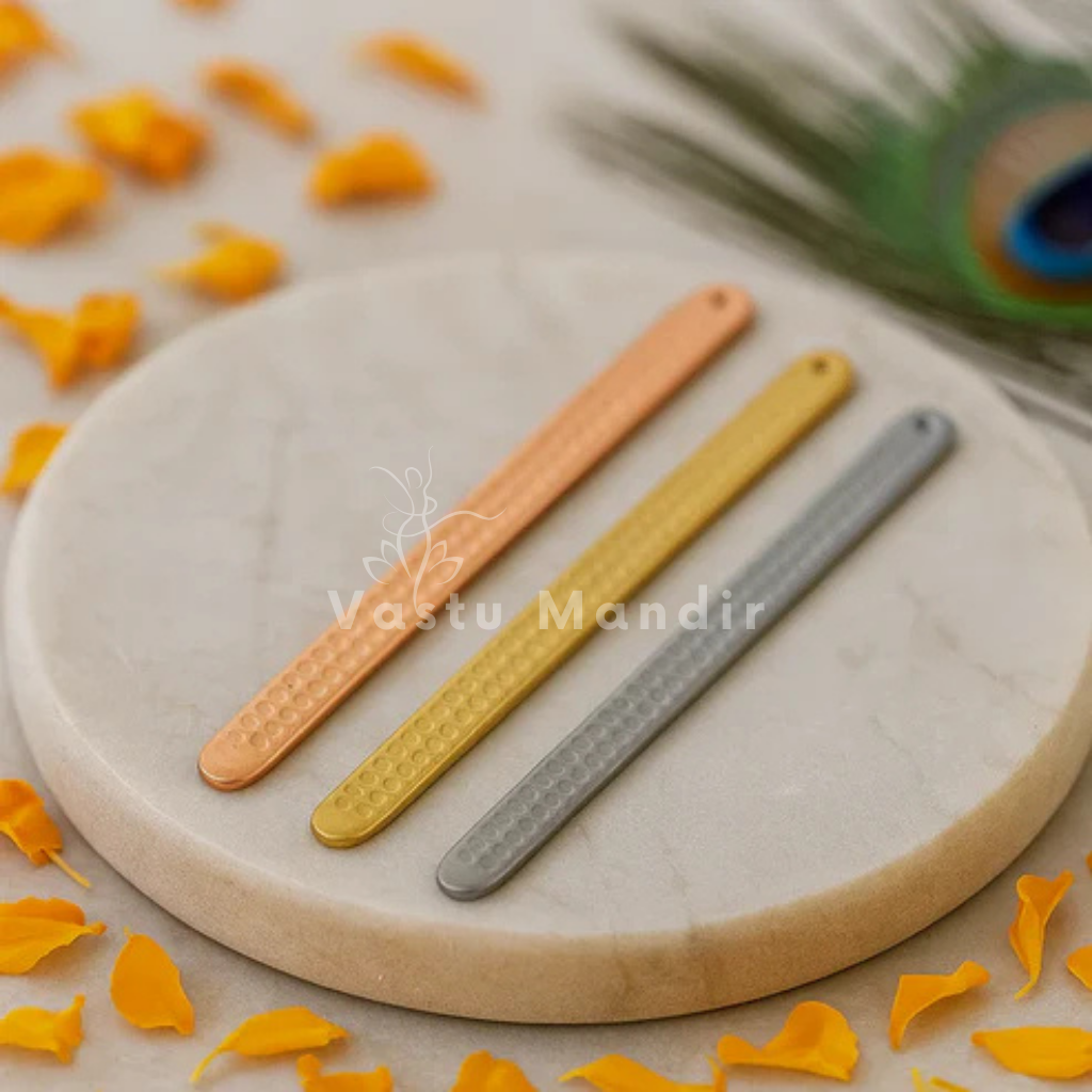 Pyramid Strip 10.5" for Vastu Remedy in Copper, Brass, and Lead on a round stone surface with peacock feathers in the background.