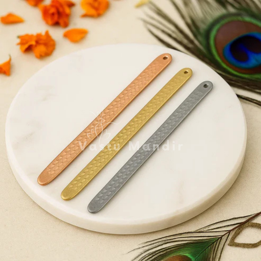 Pyramid Strip 10.5" for Vastu Remedy in Copper, Brass, and Lead on a white round surface with peacock feathers.