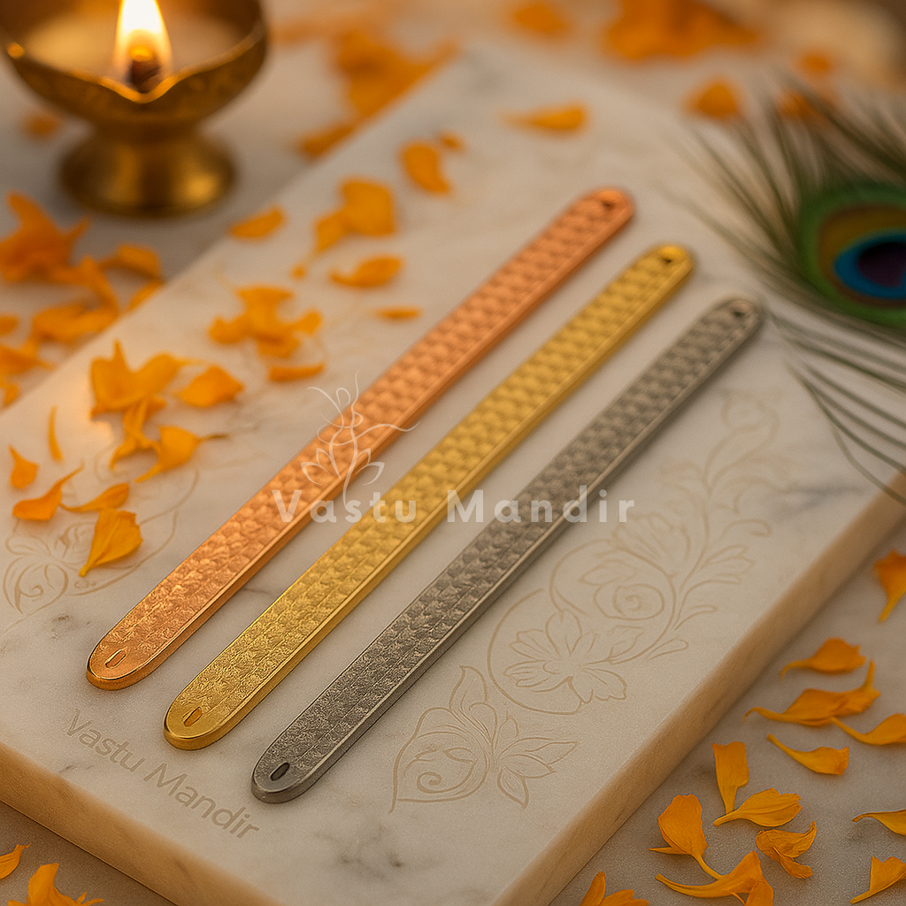 Pyramid Strip 10.5" for Vastu Remedy in Copper, Brass, and Lead on a marble surface with floral decorations and a candle.