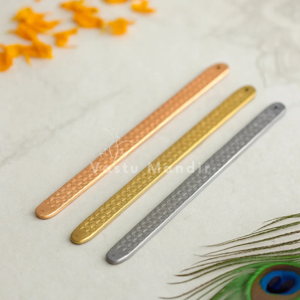 Pyramid Strip 10.5" for Vastu Remedy in Copper, Brass, and Lead on a light background with peacock feather.