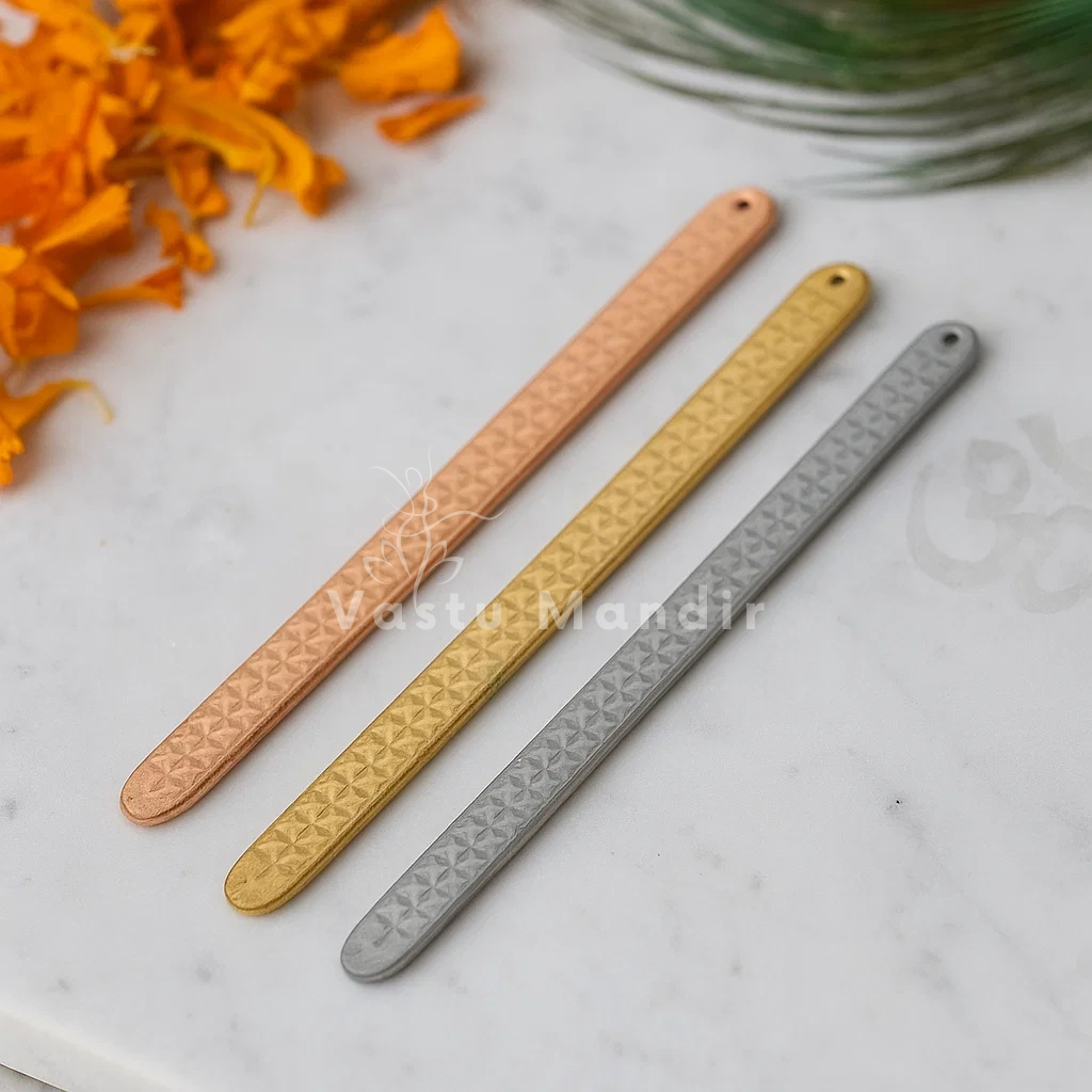 Pyramid Strip 10.5" for Vastu Remedy in Copper, Brass, and Lead on a marble surface with orange flowers.