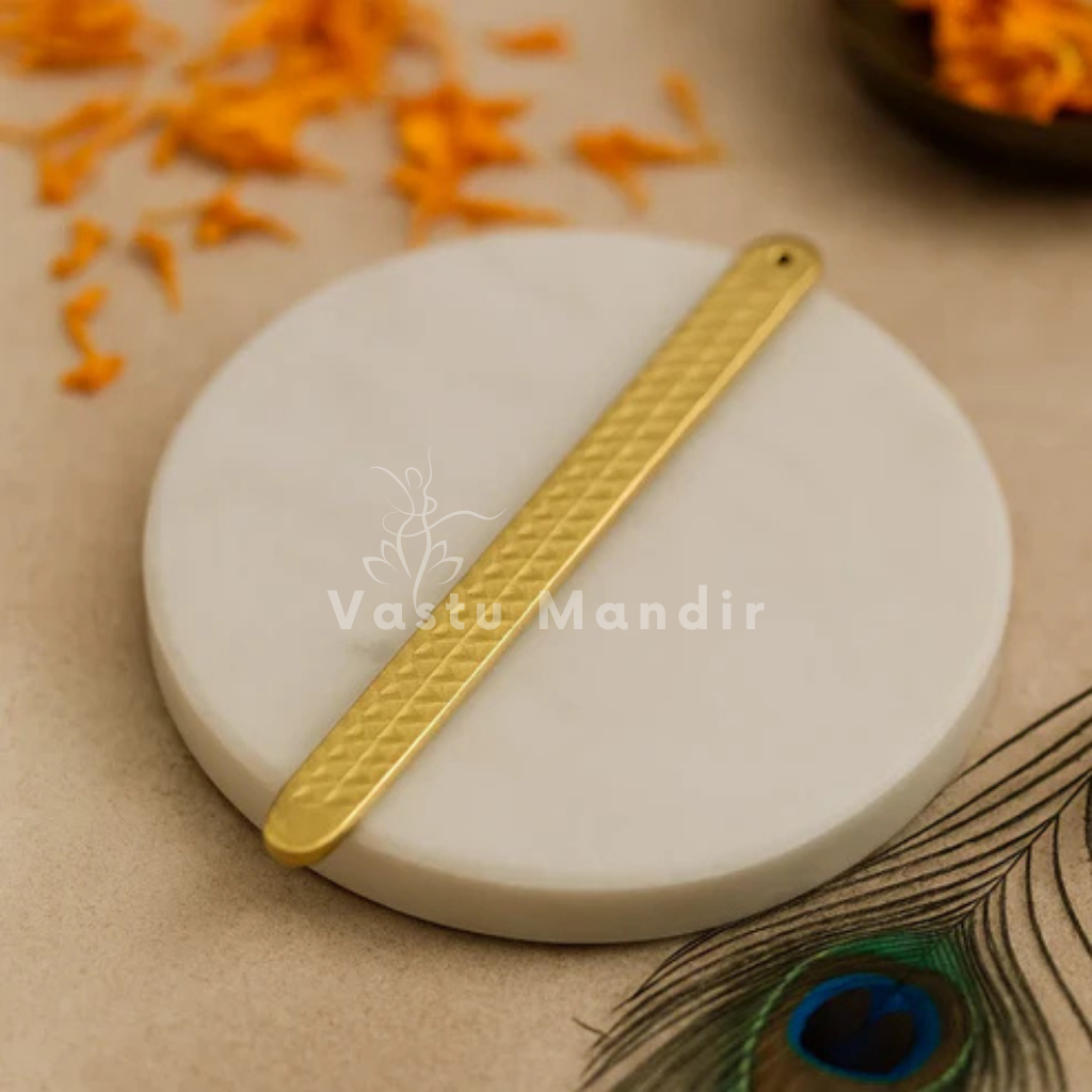 Pyramid Strip 10.5 inches for Vastu Remedy in  Brass on a white stone with 'Vastu Mandir' branding, peacock feather, and orange elements in the background.