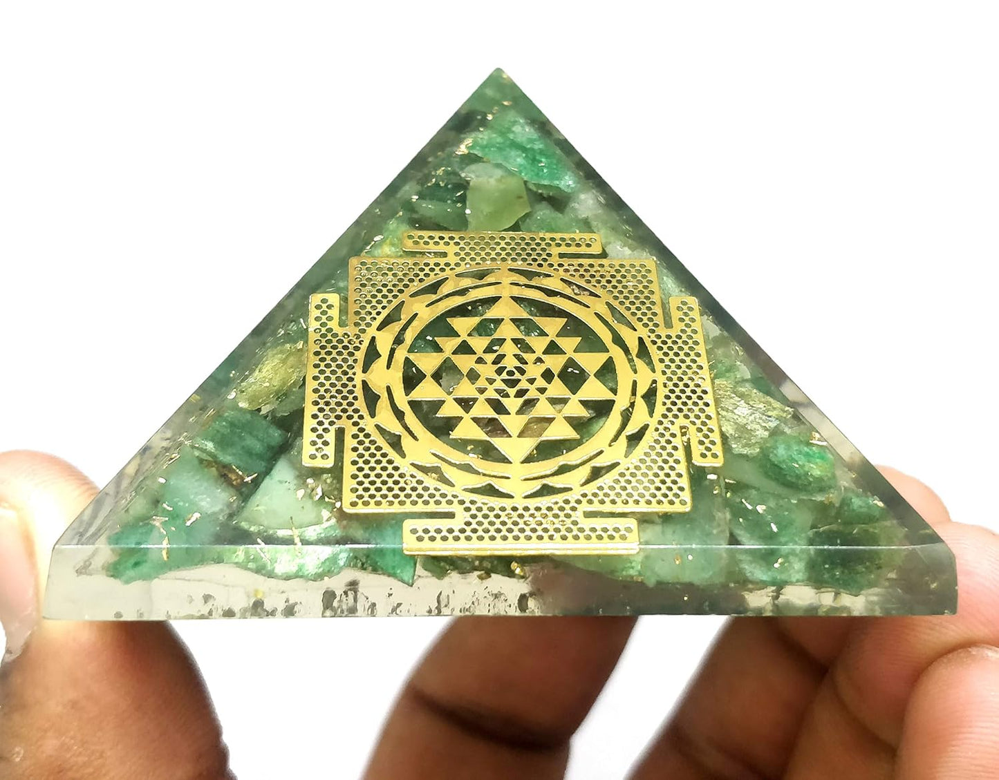 green mica shree yantra orgonite pyramid vastu remedy manifestation held by a hand against a white background