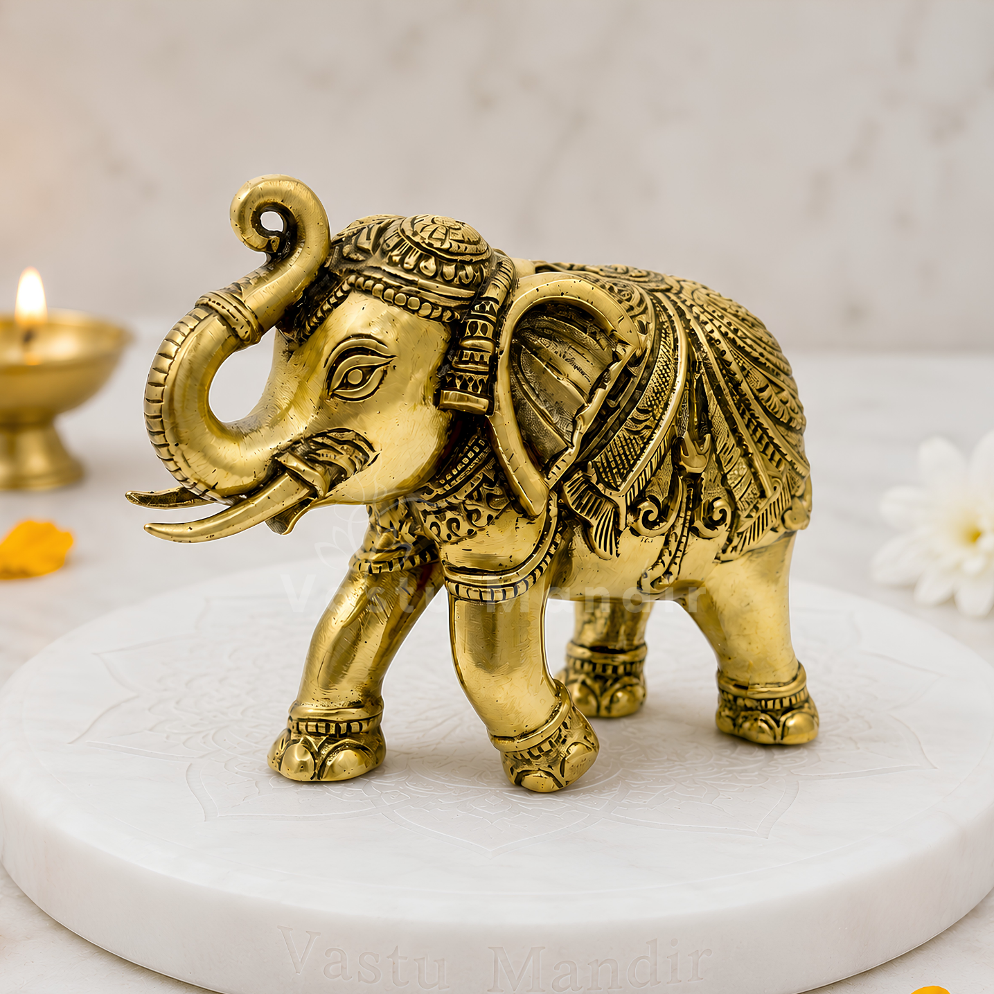 Decorative gold elephant figurine on a white platform with a soft-focus background.