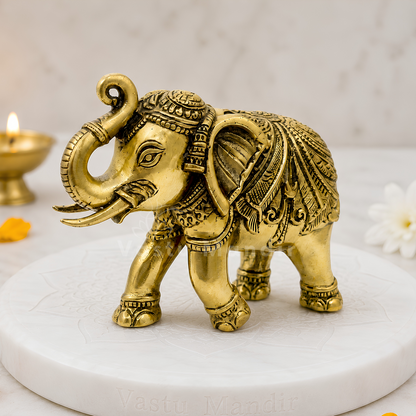 Decorative gold elephant figurine on a white platform with a soft-focus background.