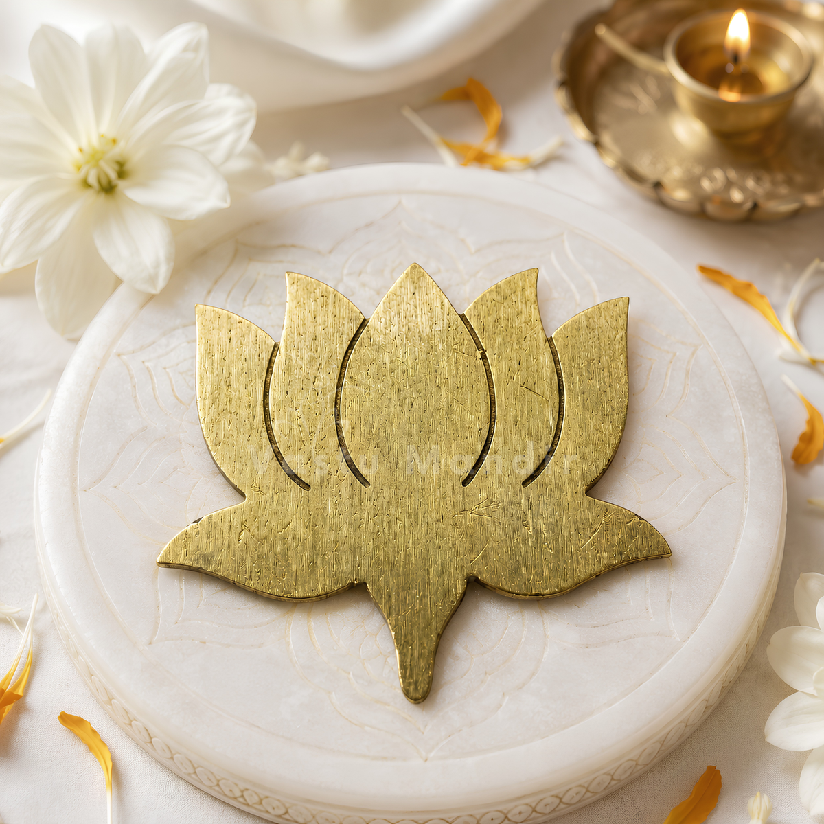 Brass lotus displayed on a white embossed plate with flowers and a brass lamp