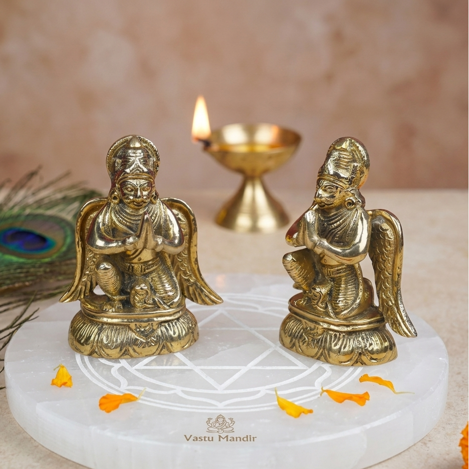 Brass Lord Garud Dev Ji Idol on a white platform with a candle and peacock feather in the background.