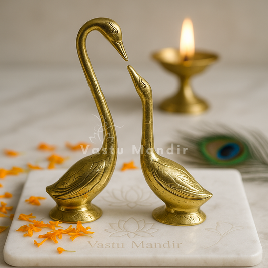 Brass Swan Pair on a marble base with a blurred candle in the background.