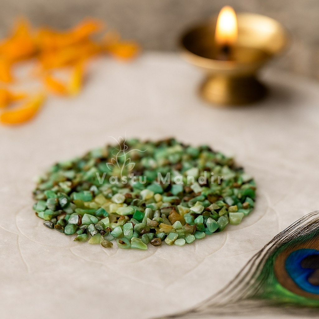 Chrysoprase Crystal Chips on a white surface with a lit candle in the background, featuring the brand 'Vastu Mandir'.