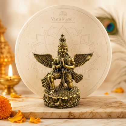 Garud Dev brass idol on a marble base with decorative flowers and sacred accents