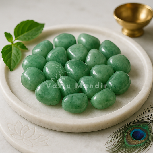 Green Aventurine Tumbled Stones on a white plate with a gold bowl and peacock feather in the background