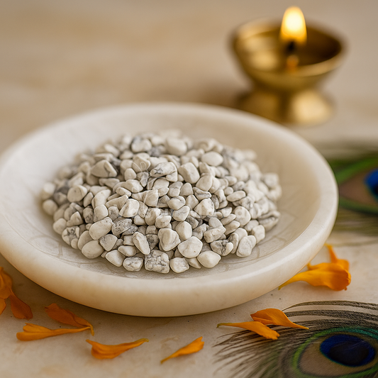 Howlite Chips in a bowl with a lit candle and peacock feather in the background