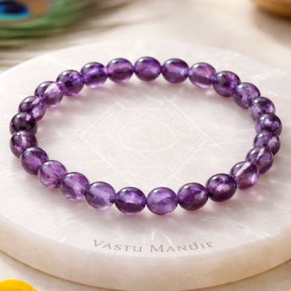 Hydro Amethyst Bracelet on a white marble surface with 'Vastu Mandir' branding, surrounded by yellow flowers.