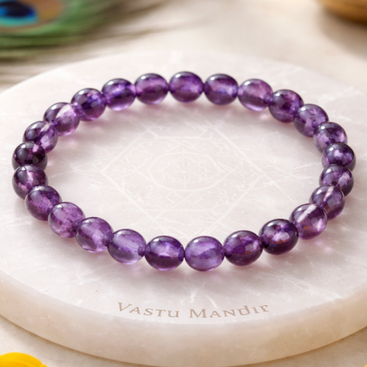 Hydro Amethyst Bracelet on a white marble surface with 'Vastu Mandir' branding, surrounded by yellow flowers.