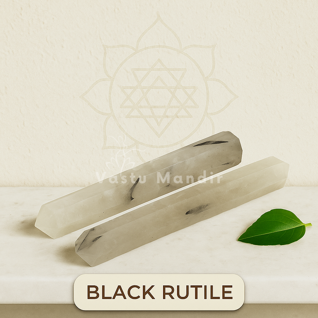 Two black rutile crystals on a beige background with a leaf and 'Rastu Mandir' branding.