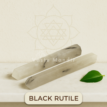 Two black rutile crystals on a beige background with a leaf and 'Rastu Mandir' branding.