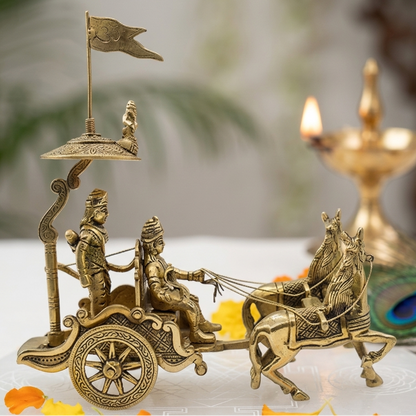 Brass chariot figurine with two figures and horses, set against a blurred background.