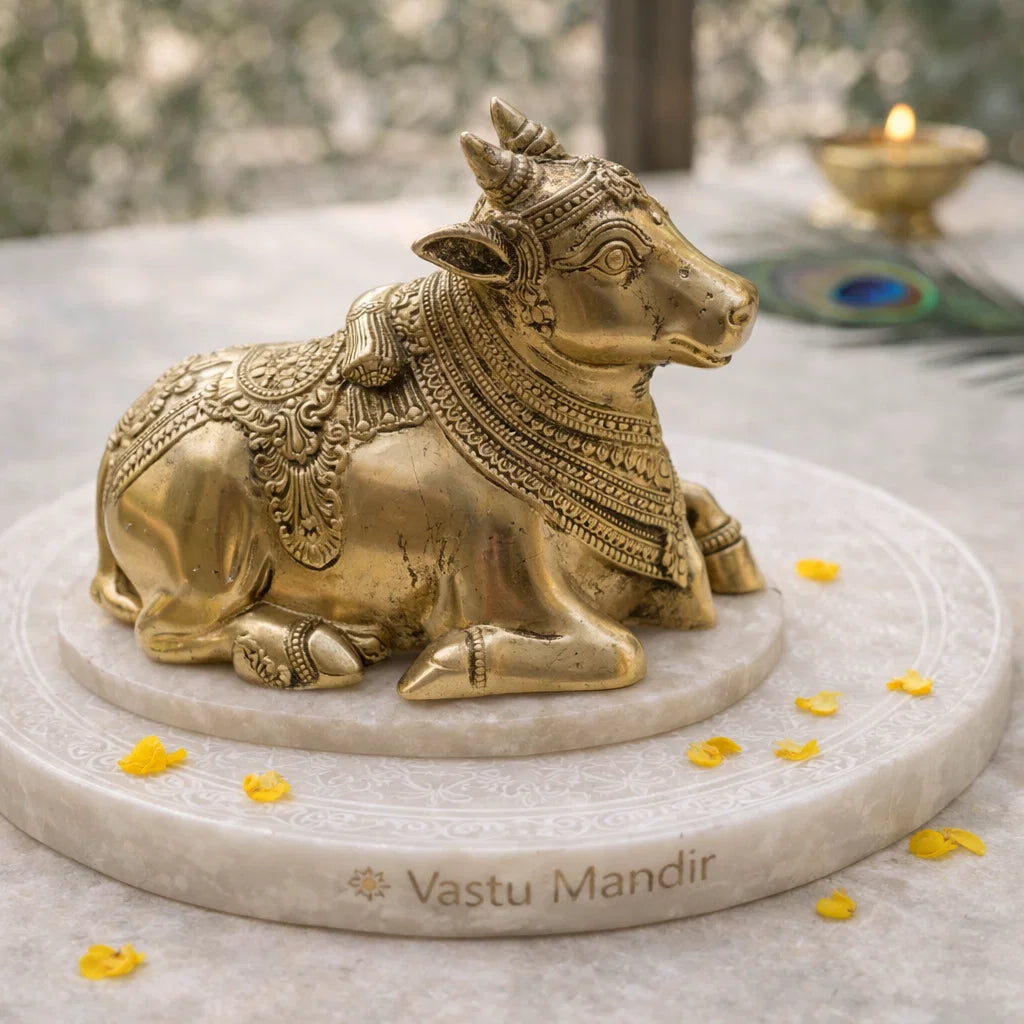 Vastu brass bull statue on a marble base with 'Vastu Mandir' branding, surrounded by yellow flowers.