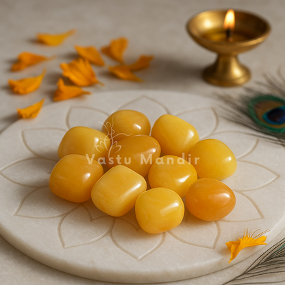 Yellow Jade Tumbled Stones on a decorative plate with a lit candle in the background