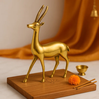 Gold deer figurine on a wooden base with orange fabric in the background