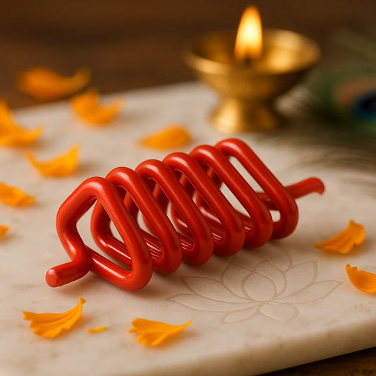 Red coiled candle on a textured surface with yellow petals and a lit gold lamp in the background.