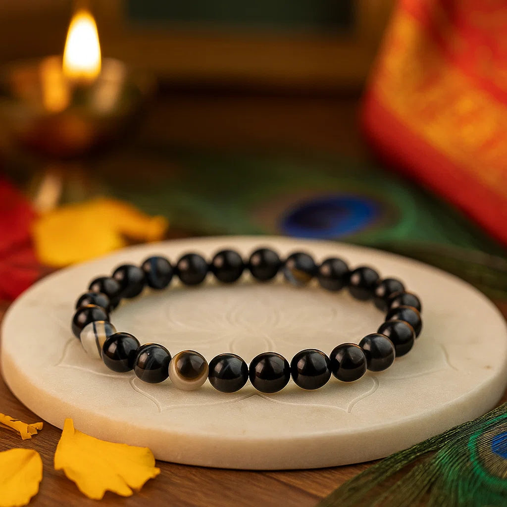 Black Agate 8mm bead bracelet on a white stone surface with Diwali decorations in the background
