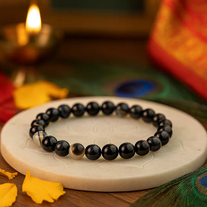 Black Agate 8mm bead bracelet on a white stone surface with Diwali decorations in the background