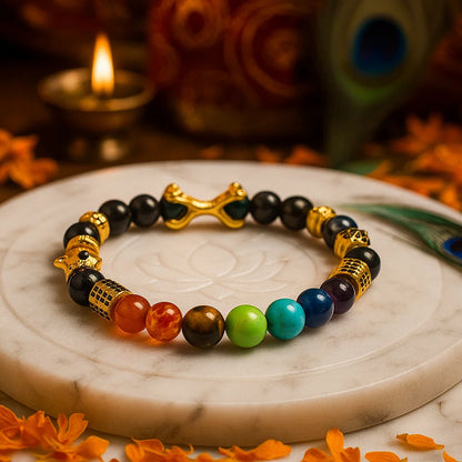 7 chakra destiny claw mala style 8mm beads bracelet on a marble surface with a peacock and candle in the background