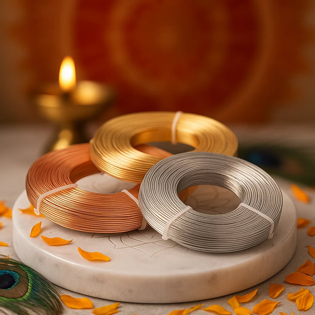 Three spools of wire in brass, silver, and copper on a marble surface with decorative elements.