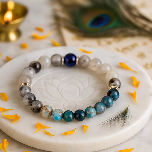 gemini zodiac crystal bracelet 8mm beads with blue and gray stones on a white dish with peacock feather and candle in the background